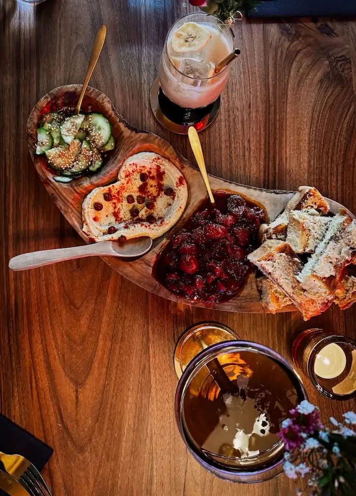 Planche à partager du restaurant Guarà à Metz avec houmous onctueux, tomates rôties, pickles de concombre au sésame et toasts briochés au beurre d’ail et miso